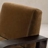 Orchid Chair in Surrey Ochre featuring plush upholstery and a sleek metal armrest.