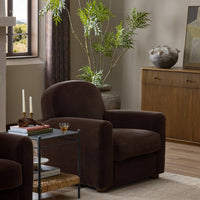 Chiara Chair in Monte Chocolate with curved back and plush upholstery in a cozy room setting.