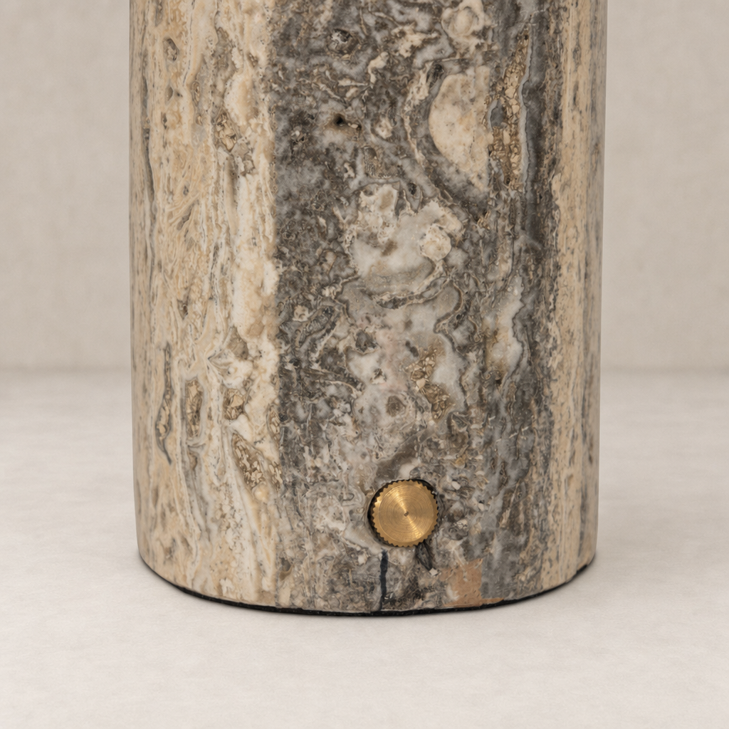 Cordless table lamp with aged antique brass iron and textured marble finish.