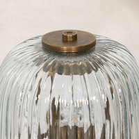 Cordless table lamp featuring aged antique brass iron and fluted glass shade.