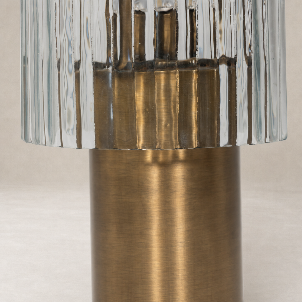 Cordless table lamp in aged antique brass iron with a ribbed glass shade.