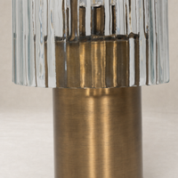 Cordless table lamp in aged antique brass iron with a ribbed glass shade.