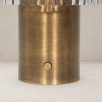 Cordless table lamp in aged antique brass iron with a sleek cylindrical base.