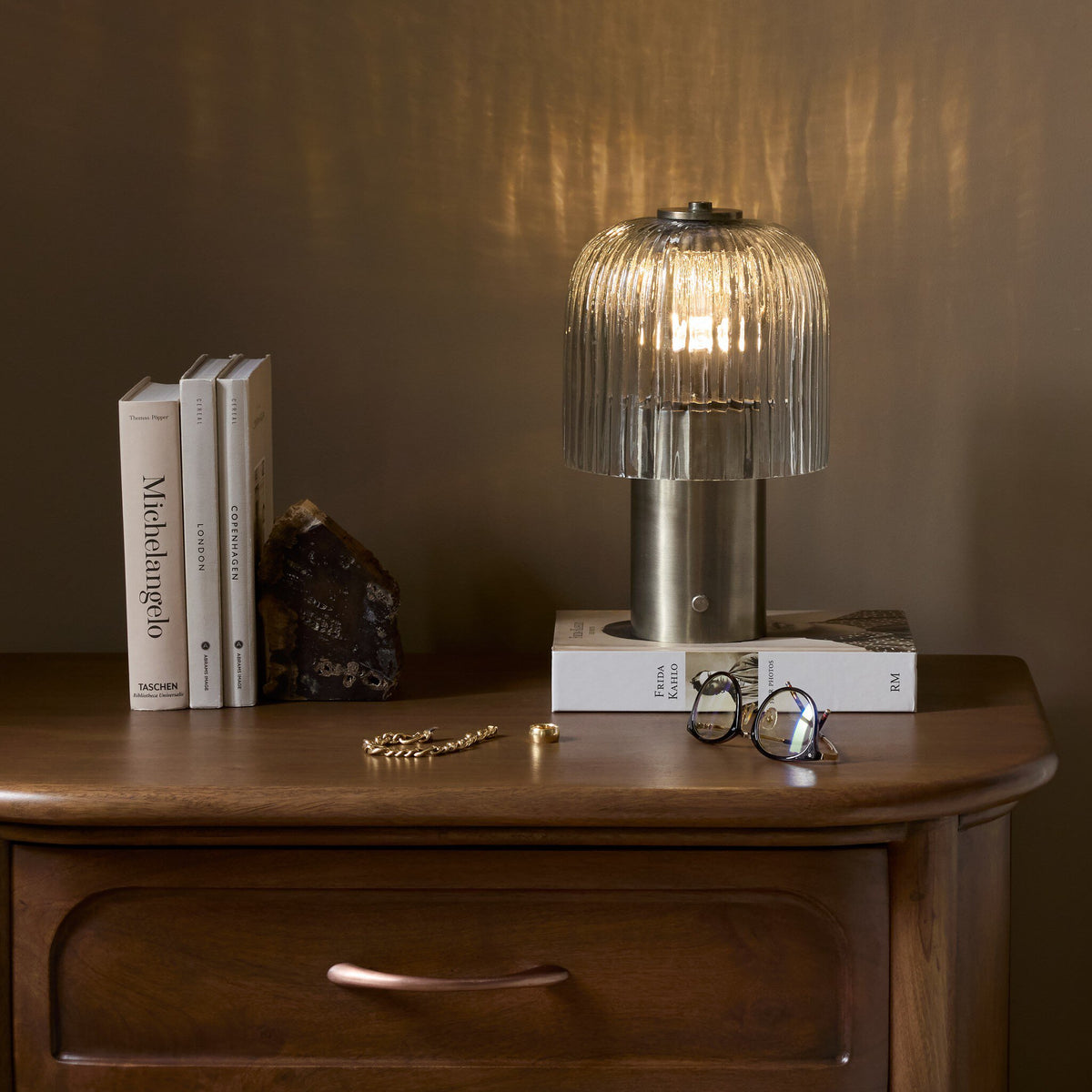 Cordless table lamp in antique nickel with pleated glass shade.