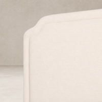Elegant bed with a soft Laughlin Bone fabric and curved headboard design.