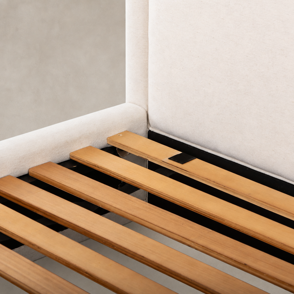Close-up of wood slats supporting a Laughlin Bone bed frame with padded headboard.