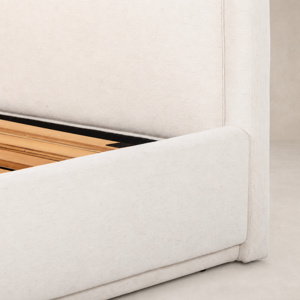 Stylish bed in Laughlin Bone upholstery with wooden slats visible underneath.