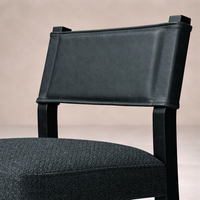 Detail of the Roseto Dining Chair showcasing its sleek black leather backrest and textured fabric seat.
