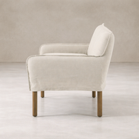 Slipcovered upholstered bench in cream fabric with a low back and wood legs.
