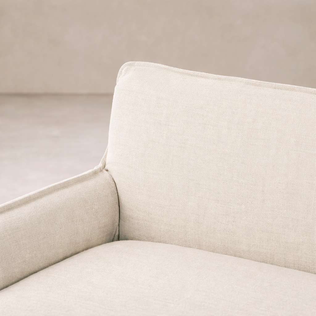 Slipcovered upholstered bench in cream fabric with a low back and wood legs.