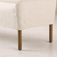 Slipcovered upholstered bench in cream fabric with a low back and wood legs.
