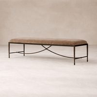 Long upholstered bench with a warm brown cushion and hand-forged iron base