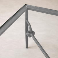 Detail of the Selene Coffee Table showcasing its sleek glass top and unique metal frame design.