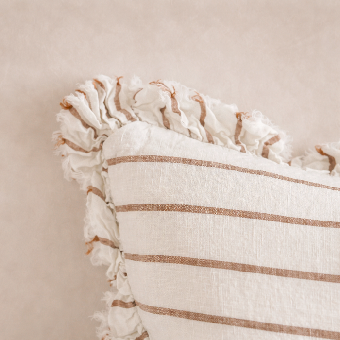 Detail of the Hallie Ruffled Linen Pillow showcasing soft brown and cream stripes with a ruffled edge.
