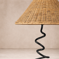 Detail of the Anya Lamp showcasing its woven rattan shade and unique spiral metal base.