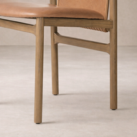 Close-up of the Marbella Dining Chair highlighting its warm leather seat and natural wood frame.