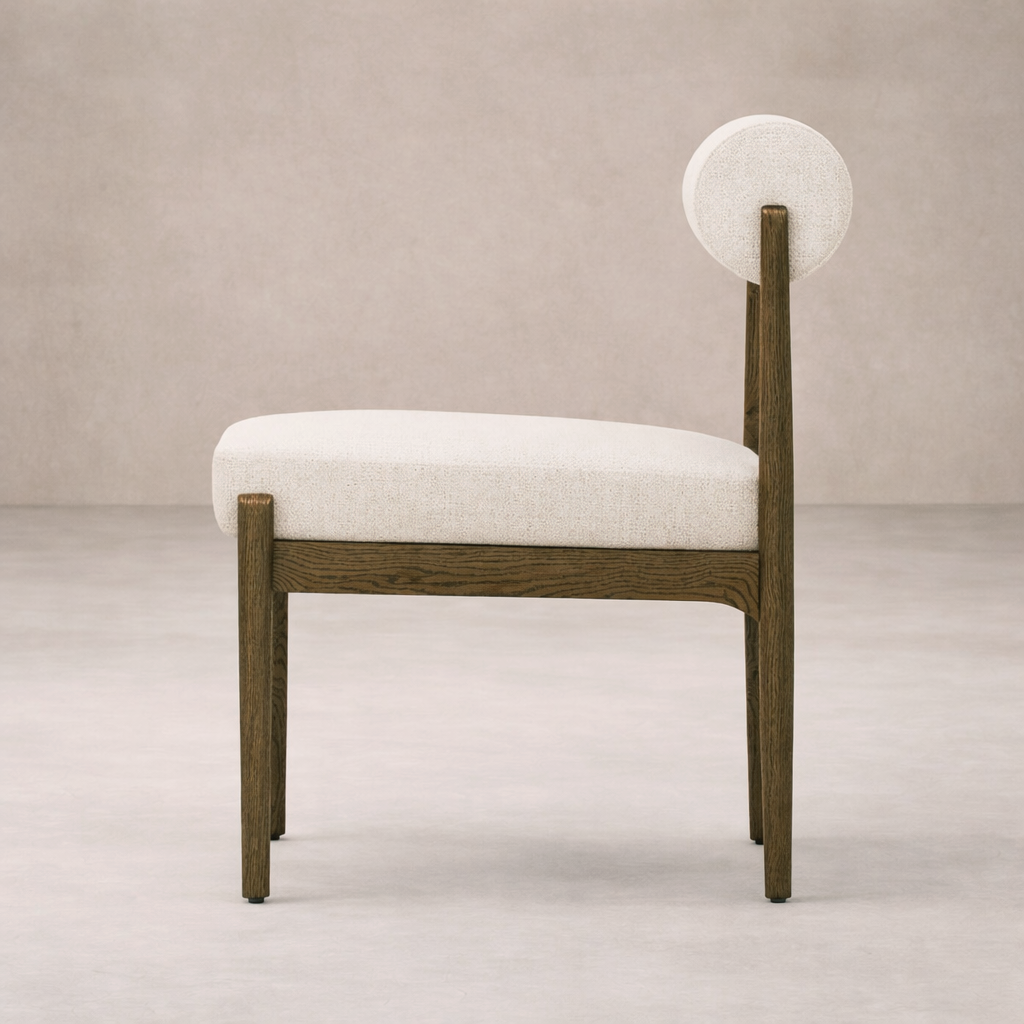 Side angle of the Calista Dining Chair featuring a light fabric seat and unique circular backrest.