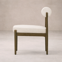 Side angle of the Calista Dining Chair featuring a light fabric seat and unique circular backrest.