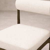 Detail of the Calista Dining Chair showcasing its soft, textured upholstery and sleek wooden frame.