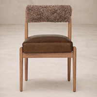 Front view of the Calista Dining Chair featuring a warm leather seat and cozy textured backrest.