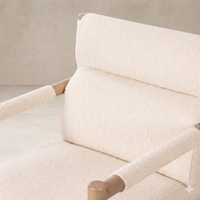Detail of the Sorrento Dining Chair showcasing its soft, textured upholstery and natural wood armrests.