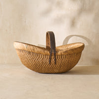 Detail of a vintage Shandong willow basket from the 1930s, showcasing intricate weaving and a sturdy leather handle.