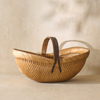 Side view of a vintage Shandong willow basket from the 1930s, featuring a leather handle and woven texture.