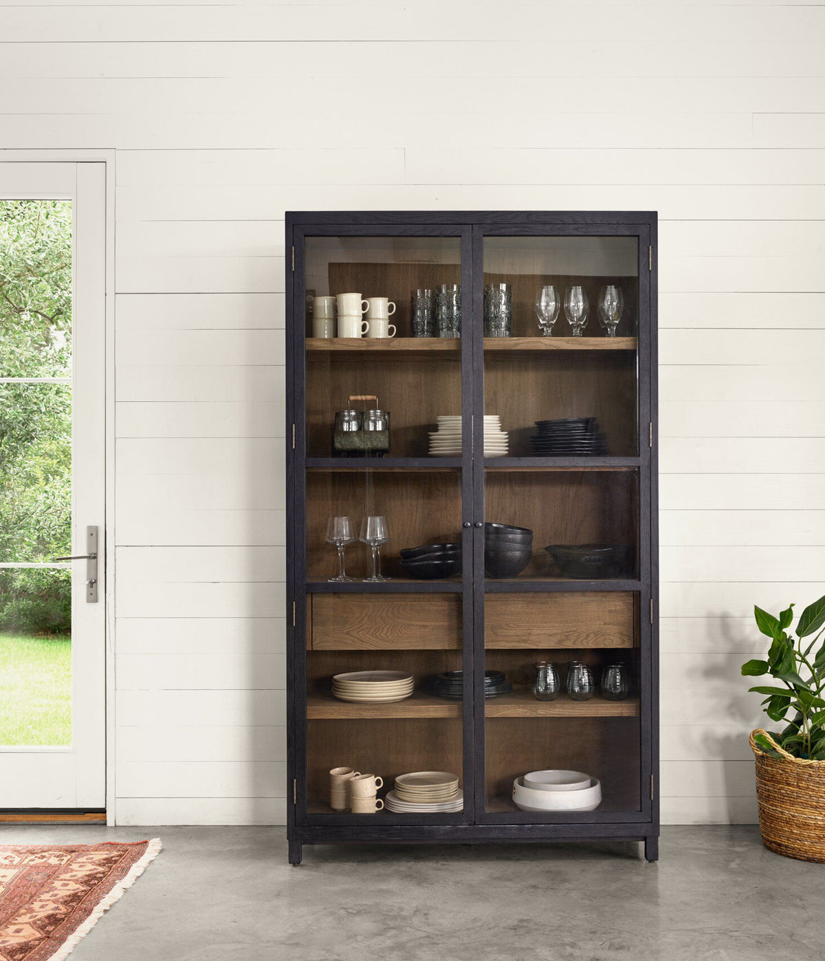 Kyra Cabinet in dark finish with glass doors displaying stylish dinnerware collection.