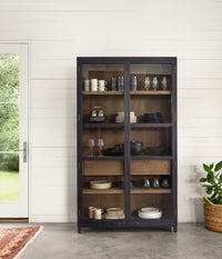Kyra Cabinet in dark finish with glass doors displaying stylish dinnerware collection.