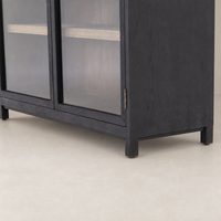 Kyra Cabinet in sleek black finish featuring clear glass doors and wooden shelving.