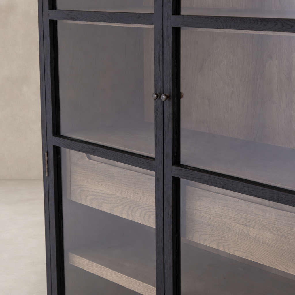 Kyra Cabinet features a sleek, black frame with glass doors and wooden shelves.