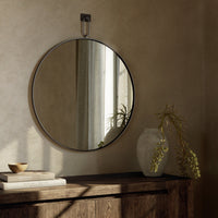 Round Vida Mirror with a sleek metal frame, reflecting natural light in a cozy room.