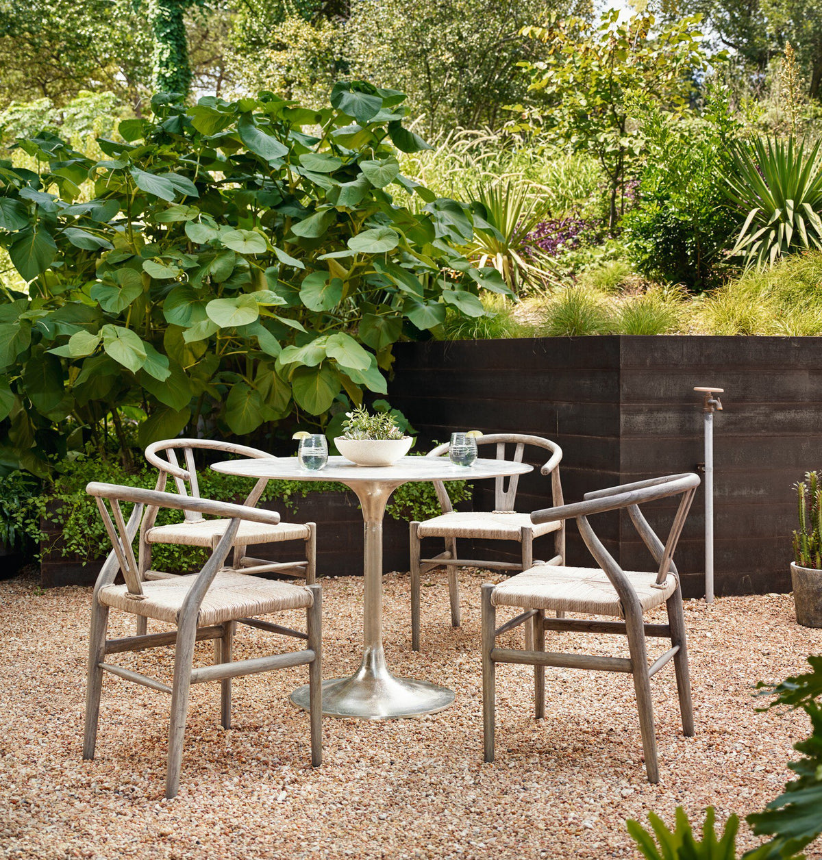 Kensington Bistro Table in raw antique nickel surrounded by rustic garden setting.