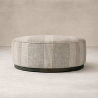 Close-up of the Bilbury Large Round Ottoman featuring a textured grey fabric and a sleek wooden base.