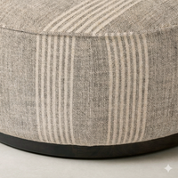 Detail of the Bilbury Large Round Ottoman showcasing its textured fabric and dark wood base.