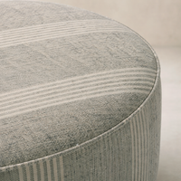 Close-up of the Bilbury Large Round Ottoman featuring a textured fabric in soft gray tones.